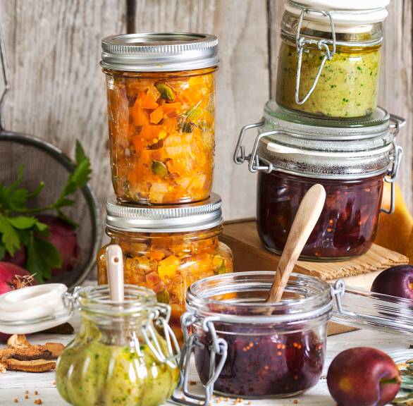 Pilzpesto und verschiedene andere eingemachte Pestos und Chutneys auf einem Tisch mit Zutaten