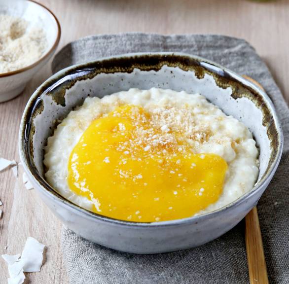 Selbstgekochter Kokos-Milchreis getoppt mit frischem Mangopüree in einer Schale