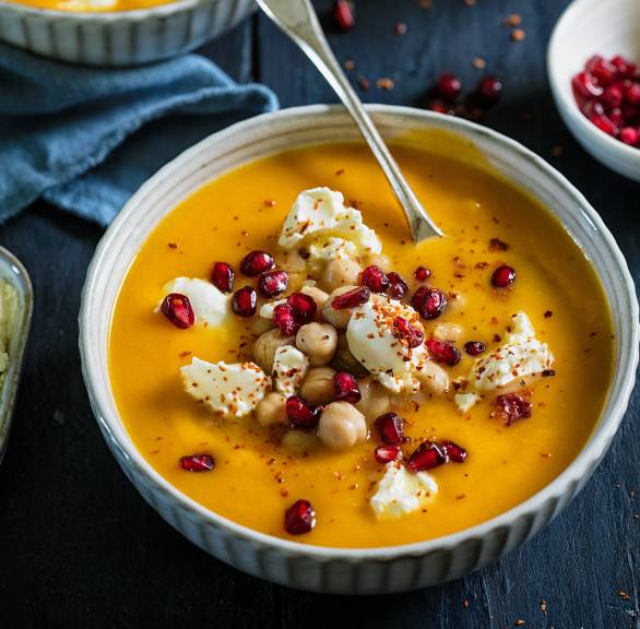 Süßkartoffelsuppe mit Kichererbsena uf zwei Suppentellern getoppt von Granatpfelkernen und Ziegenfrischkäse