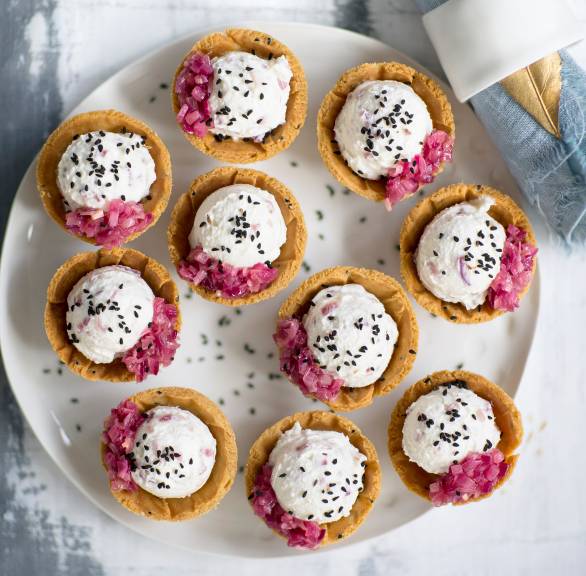 Tartelettes mit Käsecreme-Füllung getoppt von roten karamellisierten Zwiebeln und schwarzem Sesam auf einer Servierplatte