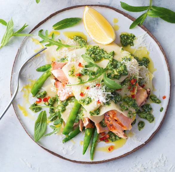 Teller-Lasagne mit Lachs und Pesto auf einem Tisch, daneben ein Schälchen Rucola