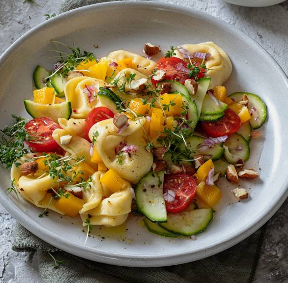 Tortellinisalat auf einem tiefen Teller getoppt mit frischer Kresse