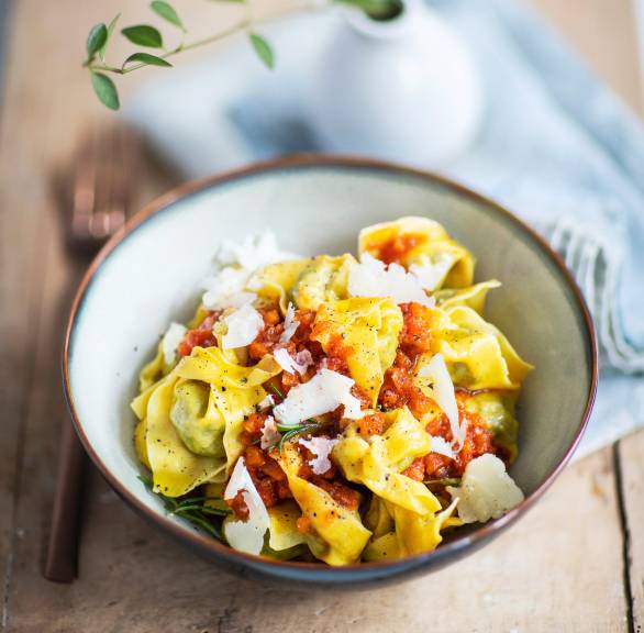 Tortelloni in einem tiefen Teller mit Tomatensauce und Parmesan getoppt