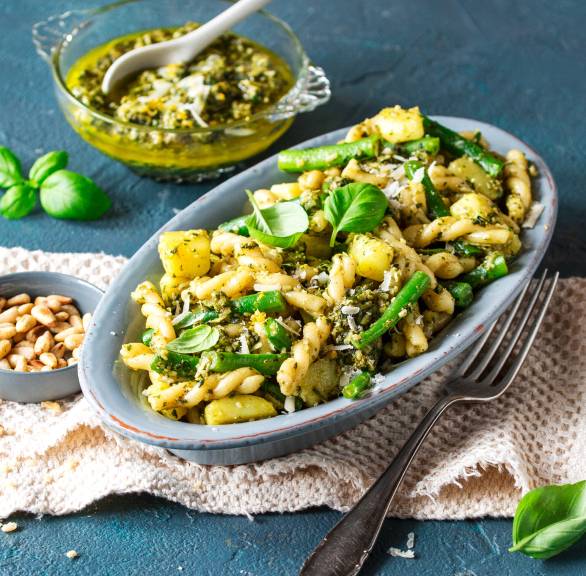 Pasta alla Genovese auf einem ovalen Teller, daneben Pesto in einem Glas