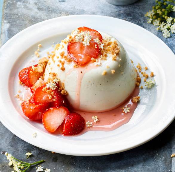 Holunderblüten-Pannacotta garniert mit Erdbeeren und Sauce auf einem Teller