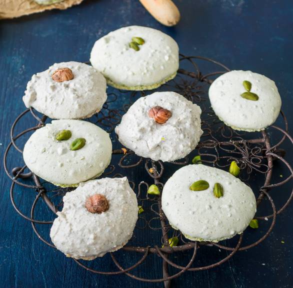 Zwei Sorten Weihnachtsplätzchen Haselnussplätzchen und Pistazien-Plätzchen auf einem Kuchengitter, daneben Weihnachtsdeko auf einem Tisch