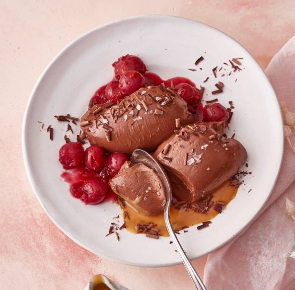 Vegane Schokomousse-Nocken angerichtet auf einem Dessertteller mit Kirschkompott und Karamellsoße