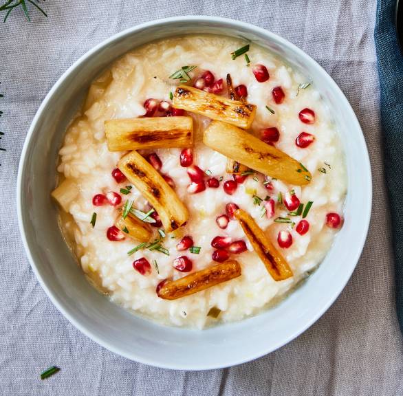 Veganes Schwarzwurzelrisotto getoppt mit Granatapfelkernen in einer Schale auf einem weihnachtlich dekorierten Tisch