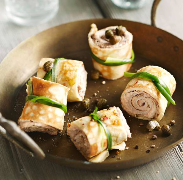 Crêpe-Röllchen mit Vitello-Tonnato-Füllung und Schnittlauch-Schnur angerichtet in einer kupfernen Pfanne