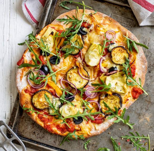 Runde Vollkorn-Pizza belegt mit Gemüse und Mozzarella auf einem Backblech
