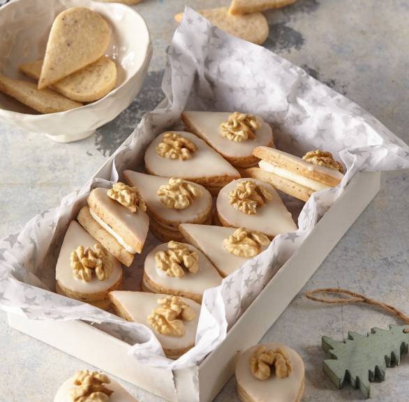 Walnussplätzchen in Tropfenform in einer Schachtel, daneben Weihnachtsdekoration