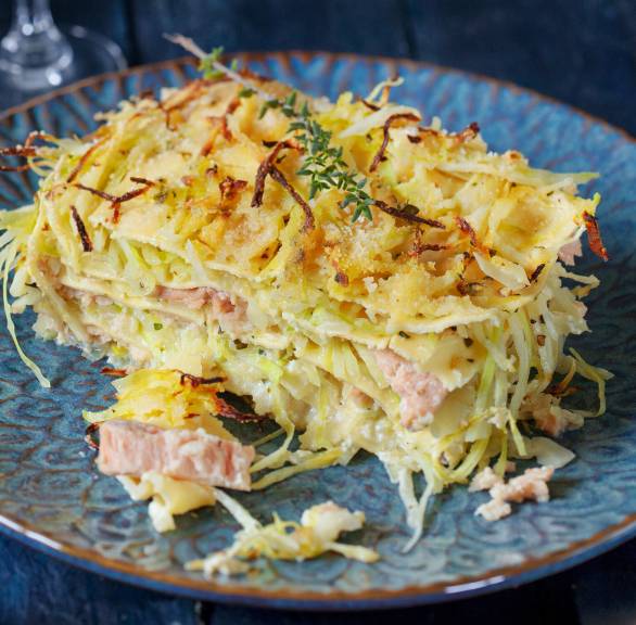 Stück weißer Lasagne auf einem blauen Teller, Lachsüllung erkennbar