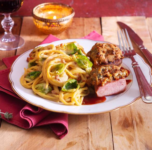 Zwei gratinierte Wildschweinmedaillons angerichtet mit Rosenkohl-Carbonara auf einem Teller