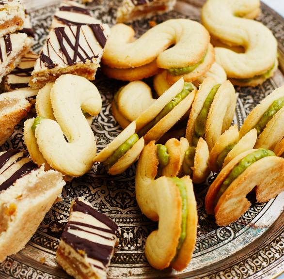 Doppeldecker-Spritzgebäck gefüllt mit Pistaziencreme auf einem Plätzchenteller neben anderen Weihachtsplätzchen