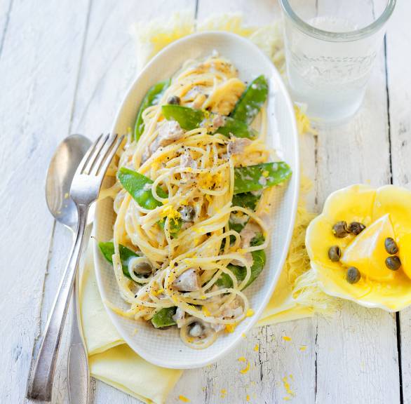 Spaghettini in einer Sauce aus Mascarpone, Zitrone, Thunfisch und Zuckerschoten angerichtet auf einem tiefen Teller