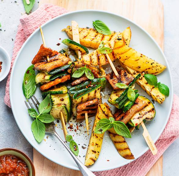 Gegrillte Zucchini-Bauchfleisch-Grillspieße angerichtet auf einem Teller mit Kartoffelspalten