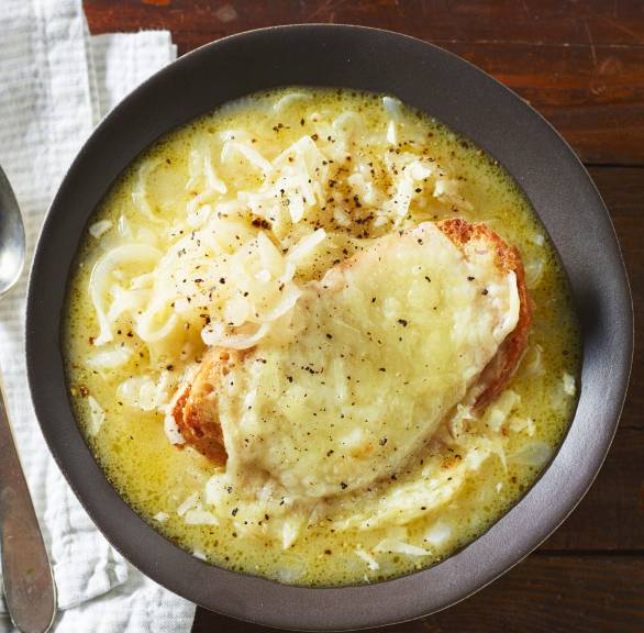 Italienische Zwiebelsuppe in einem Suppenteller getoppt von einer Scheibe mit Käse überbackenem Ciabatta