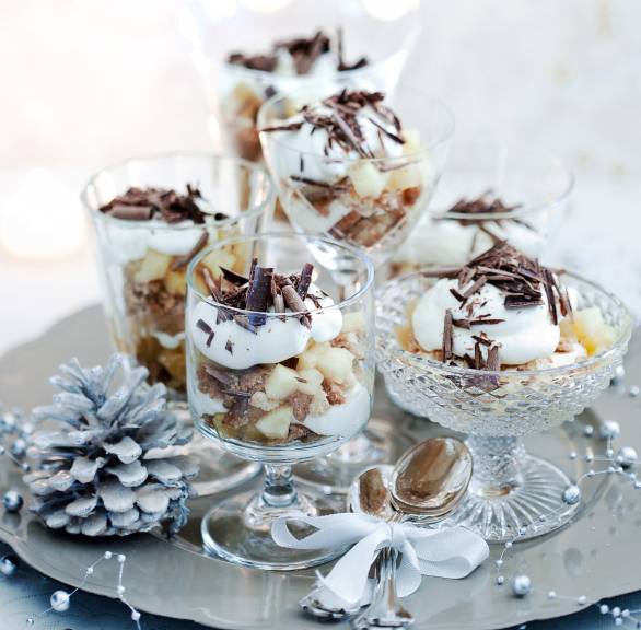 Mehrere Apfel-Mascarpone-Schichtdesserts in unterschiedlichen Gläsern auf einer silbernen Platte auf einem weihnachtlich dekorieren Tisch
