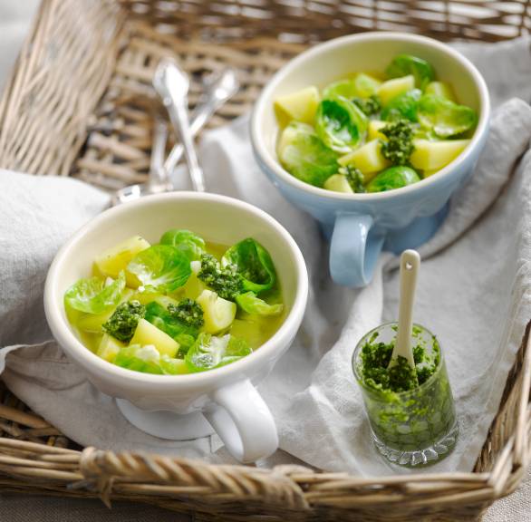 Italienischer Rosenkohleintopf in zwei Suppenschalen mit Kartoffeln, darauf und daneben grünes Pesto