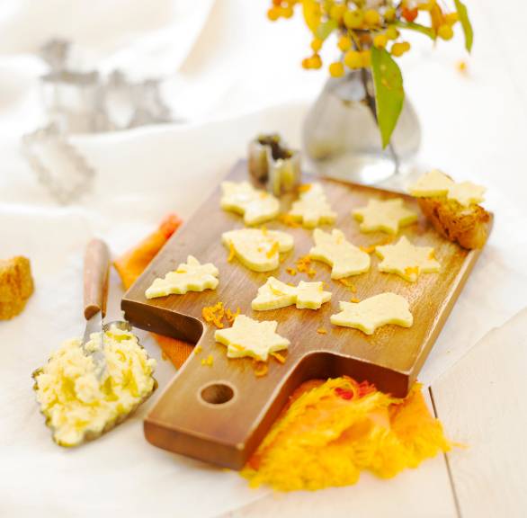 Weihnachtsbutter mit Orangen-Vanille-Aroma ausgestochen zu Weihnachtsbäumen, herzen und Sternen auf einem Holzbrett