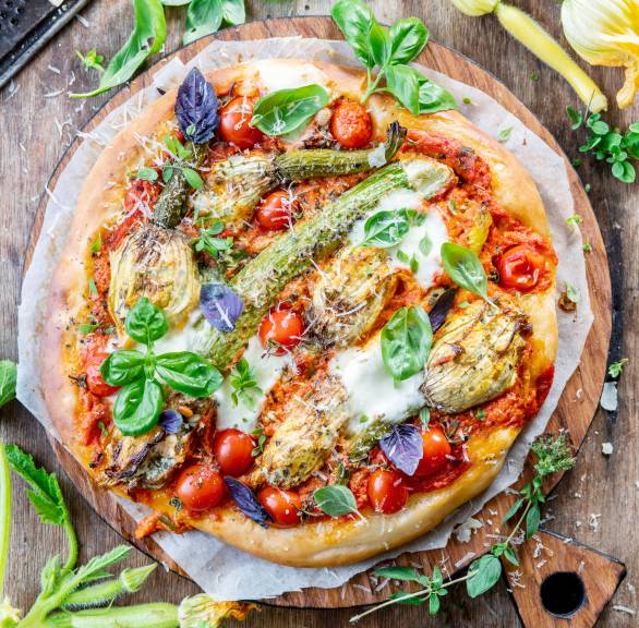 Pizza mit Tomaten und gefüllten Zucchiniblüten