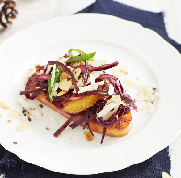 Ein Rotkohl-Crostini auf einem Teller getoppt mit Orange, Mandeln und Parmesan