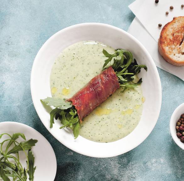  Rucola-Kartoffelcremesuppe in einem Suppenteller mit Einlage aus Rucola-Parmaschinken-Röllchen