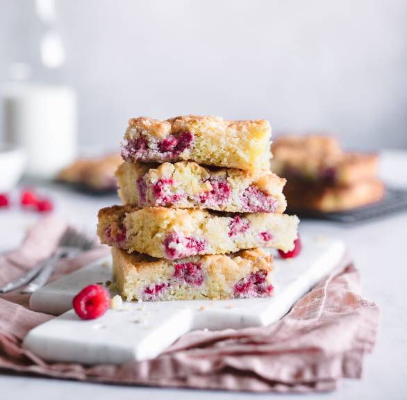 Vier Stücke Streuselkuchen mit Himbeeren vom Blech gestapelt auf einem Kuchenteller