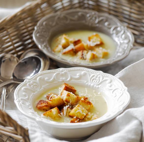 Weinsuppe mit Parmesan auf zwei Suppentellern getoppt von und Zimtcroûtons auf einem Weidentablett