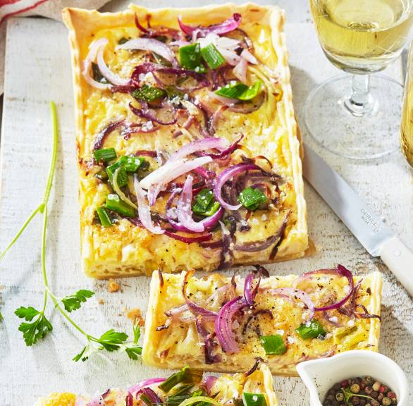 Rechteckige Zwiebelquiche in Streifen geschnitten auf einem Teller