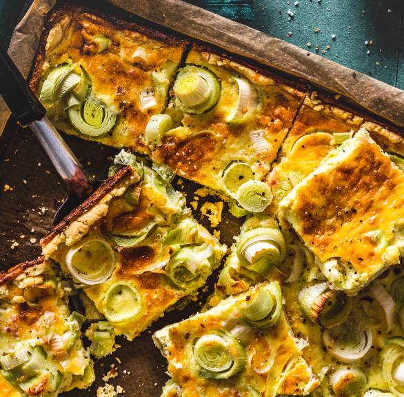 Quiche Lorraine auf einem Backblech in Quadrate geschnitten