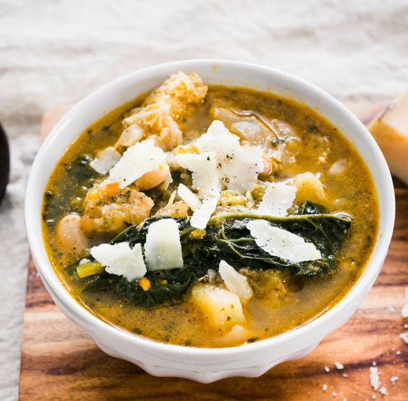 Kohlsuppe in einer Suppenschale mit Einlage aus Brot und Kohl getoppt mit Parmesanspänen