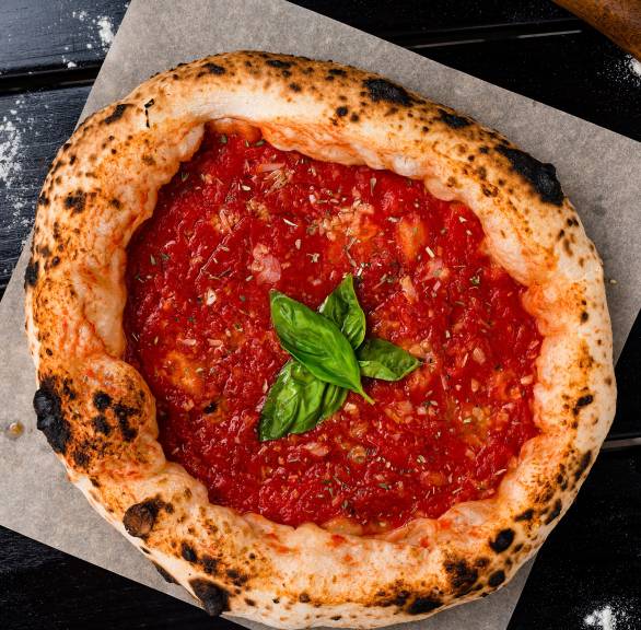 Runde Pizza Marinara im Ganzen auf einem Holzbrett garniert mit Basilikum
