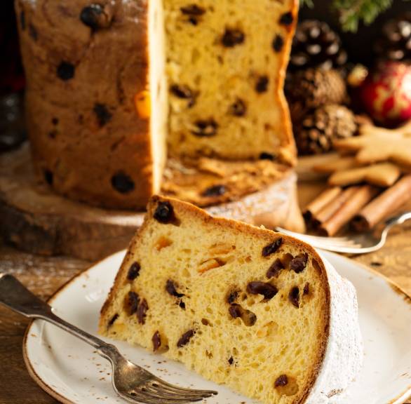 Panettone angeschnitten auf einem Teller, davor ein Stück in Nahaufnahme