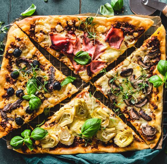 Pizza Quattro Stagioni auf einem Backblech in vier Teile geschnitten