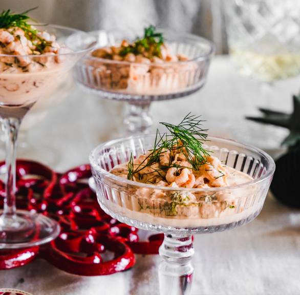Krabbencocktail in Sektgläsern angerichtet auf einem weihnachtlich dekorierten Tisch