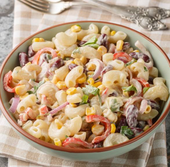 Pastasalat mit Mayonnaise in einer Salatschüssel auf einem Tisch