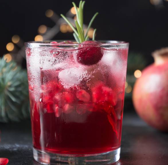 Prosecco-Cocktail mit Granatapfel in einem Cocktailglas auf einem festlich gedeckten Tisch