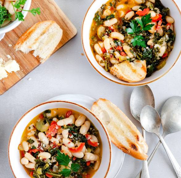 Ribollita Gemüsesuppe verteilt auf zwei Suppenteller, daneben geröstetes Ciabatta