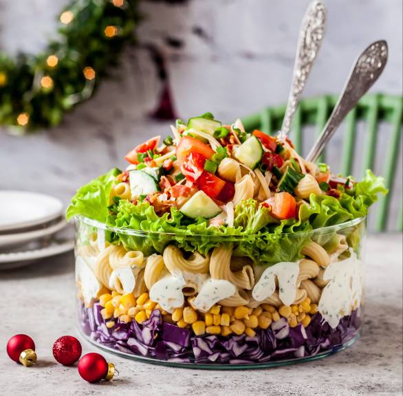 Schichtsalat in einer Glasschüssel in einem weihnachtlich dekorierten Wohnzimmer