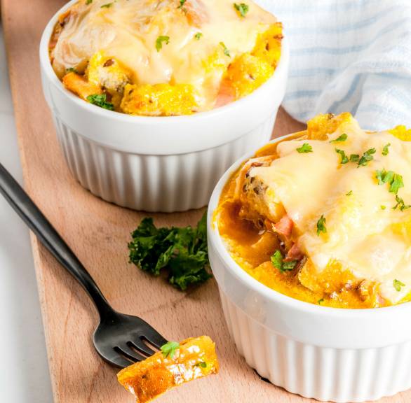 Zuppa Gallurese Brotauflauf in zwei runden Auflaufformen mit Käse überbacken auf einem Holztisch