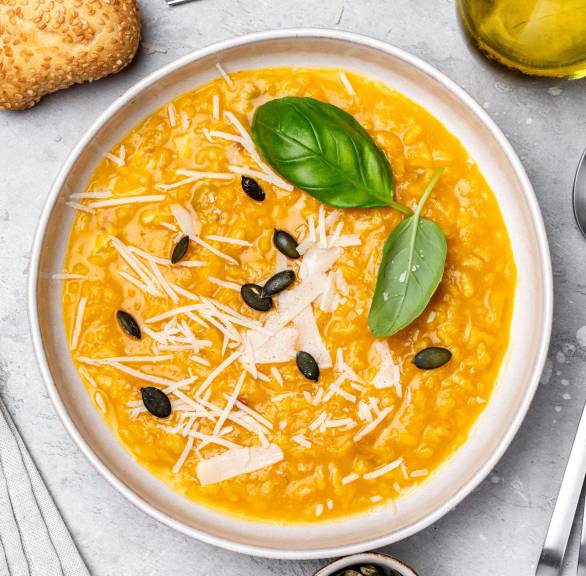 Risotto alla milanese in einem Teller, daneben Zutaten wie Parmesan und Olivenöl