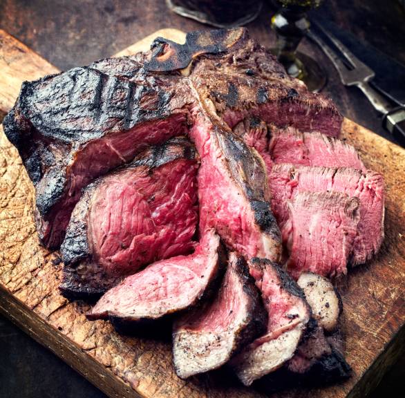 Steak Florentiner Art angeschnitten auf einem Holzbrett