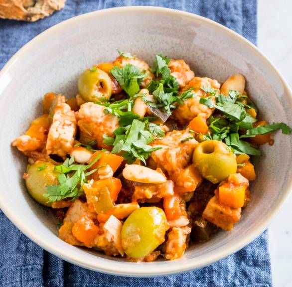 Tempeh Caponata auf einem Teller, daneben zwei Scheiben Baguette