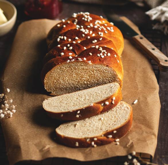 Osterzopf mit Hagelzucker angeschnitten auf einem Stück Backpapier