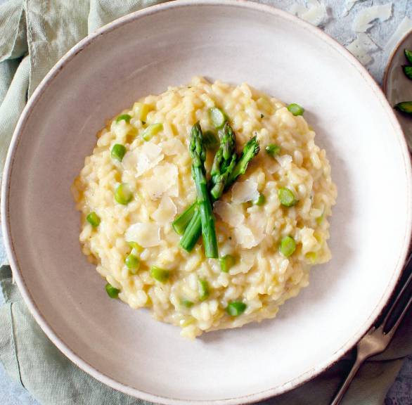 Spargelrisotto mit grünem Spargel angerichtet auf einem runden Teller 