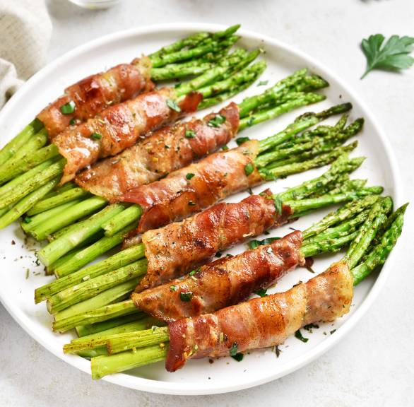 Grüner Spargel im Schinkenmantel aus dem Ofen in mehreren Päckchen auf einem Teller