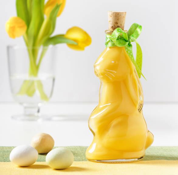 Selbst gemachter Eierlikör in einer Flasche in hasenform auf einem österlich dekorierten Tisch