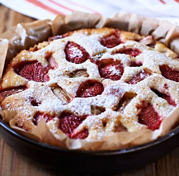 Runder Erdbeer-Rhabarber-Kuchen in einer Springform bestäubt mit Puderzucker