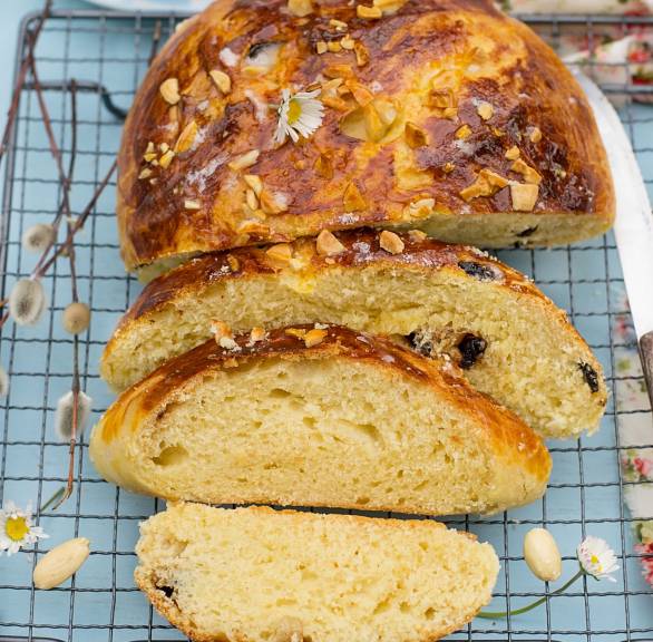 Osterbrot mit Rosinen und Mandeln bestreut angeschnitten auf einem Kuchengitter
